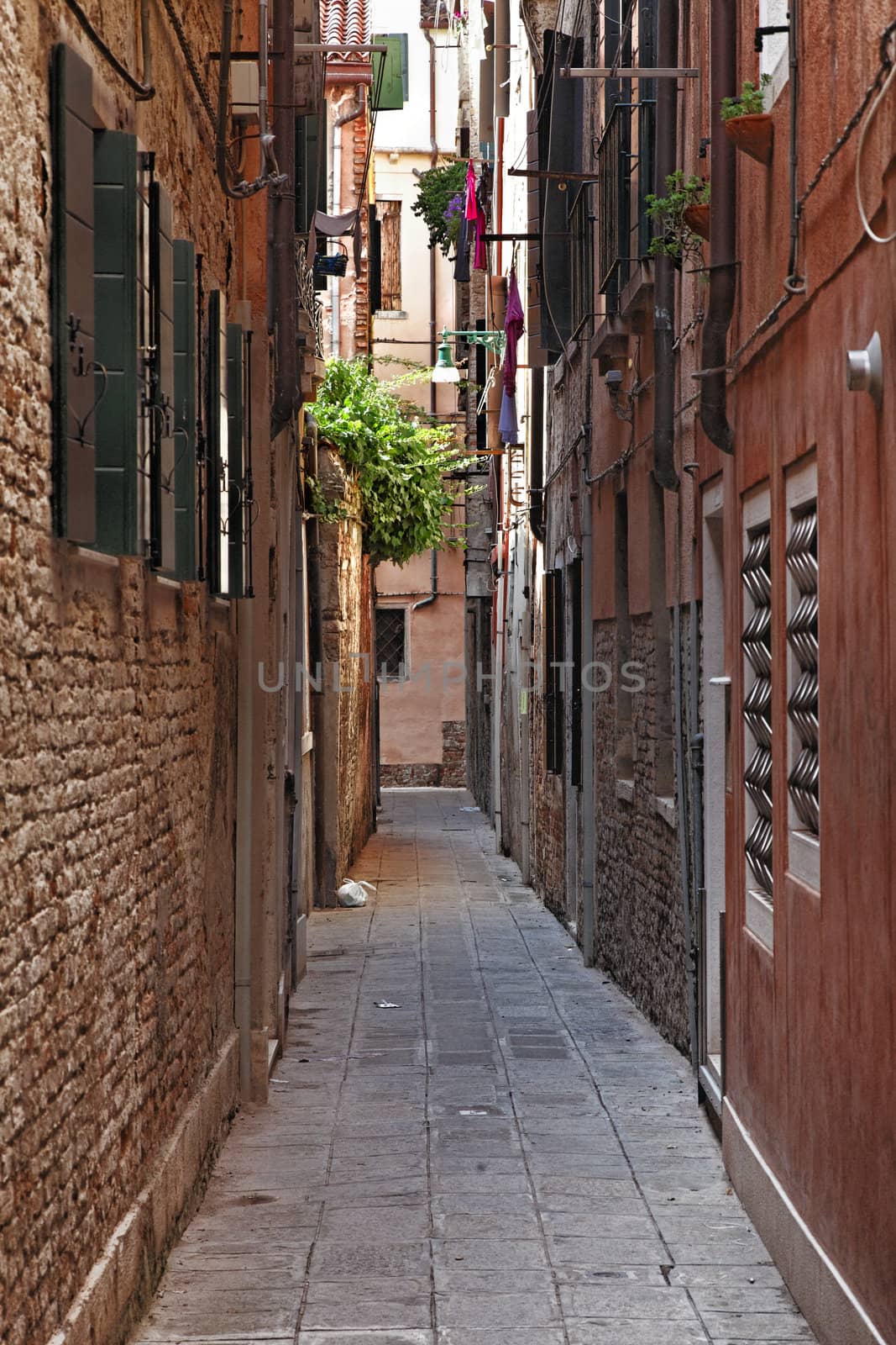 Image of a typical narrow street between walls of houses in Venice.