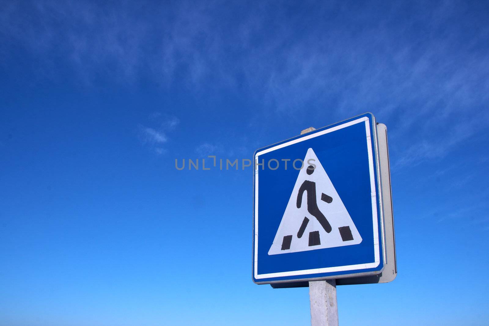 Road pedestrian crossing sign against clear deep blue sky