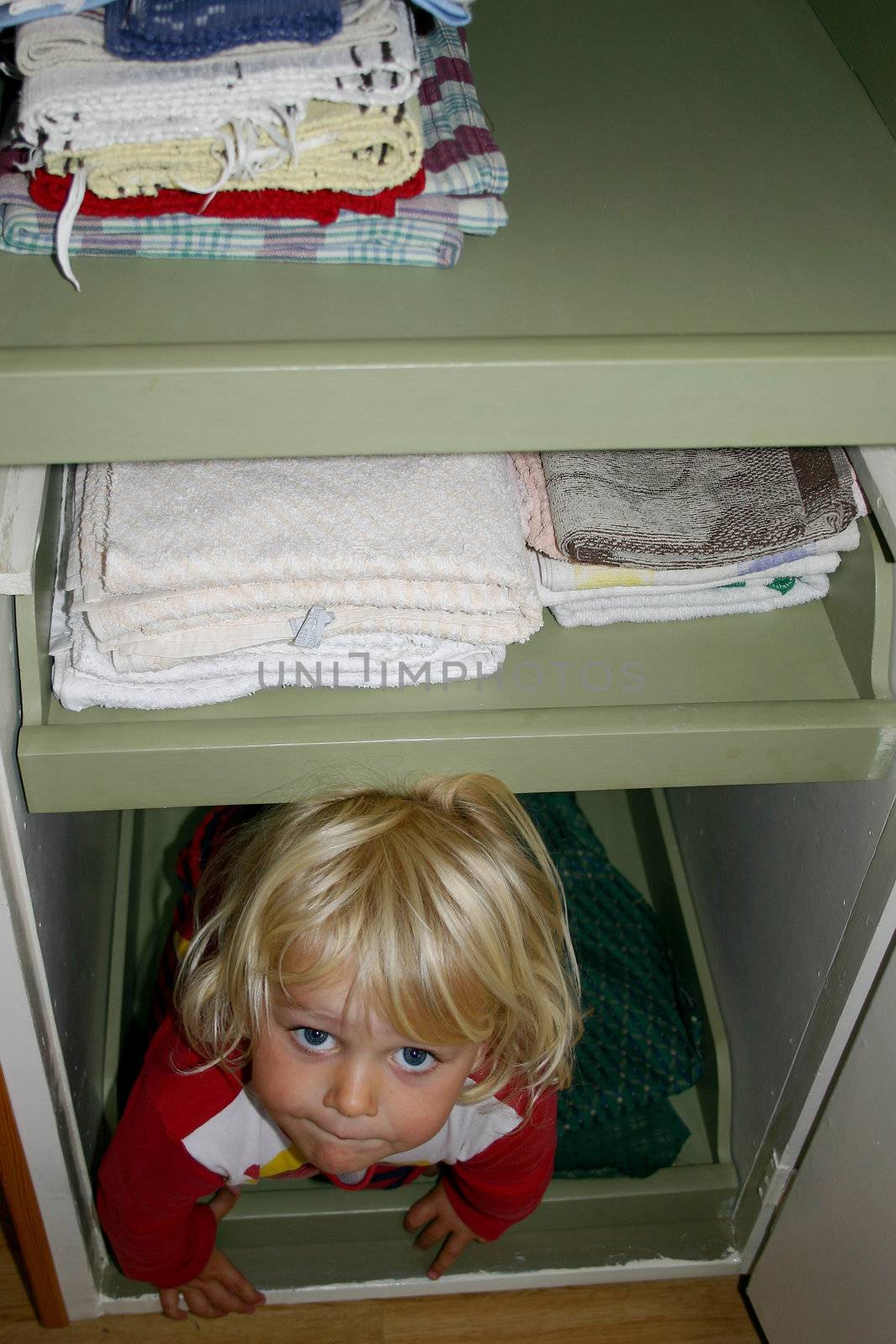 A toddler hiding in the cupboard