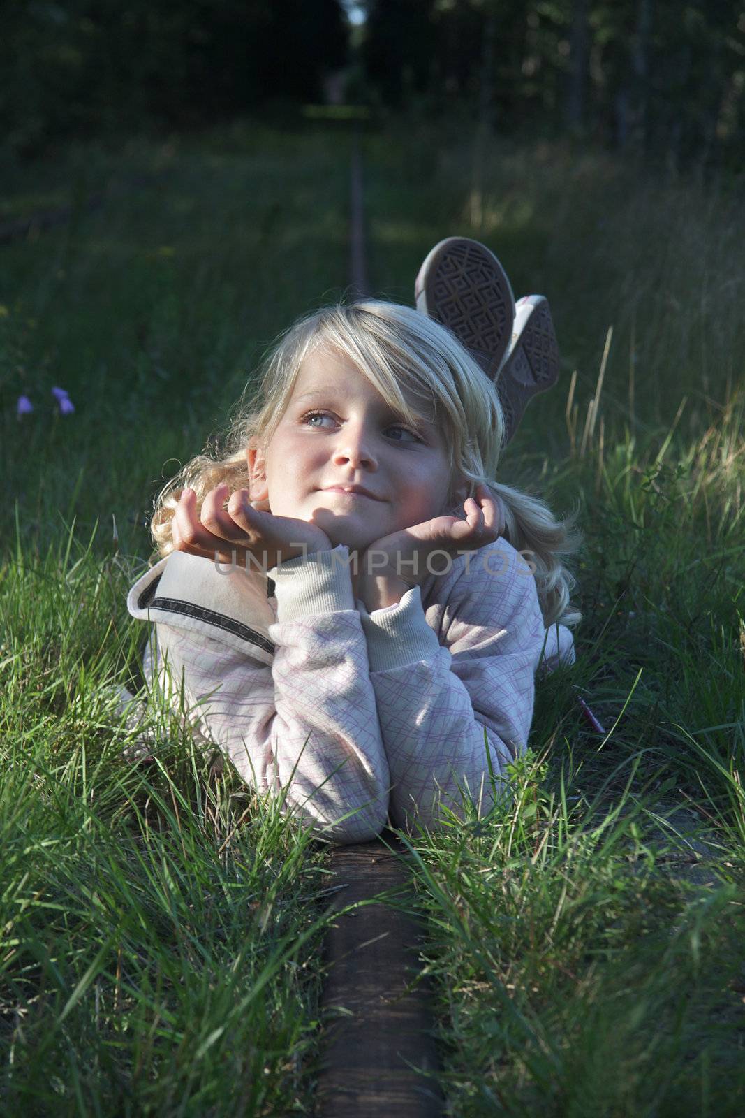 An 8 year old lying on an abandoned rail road track in the forest, daydreaming. Positive feeling