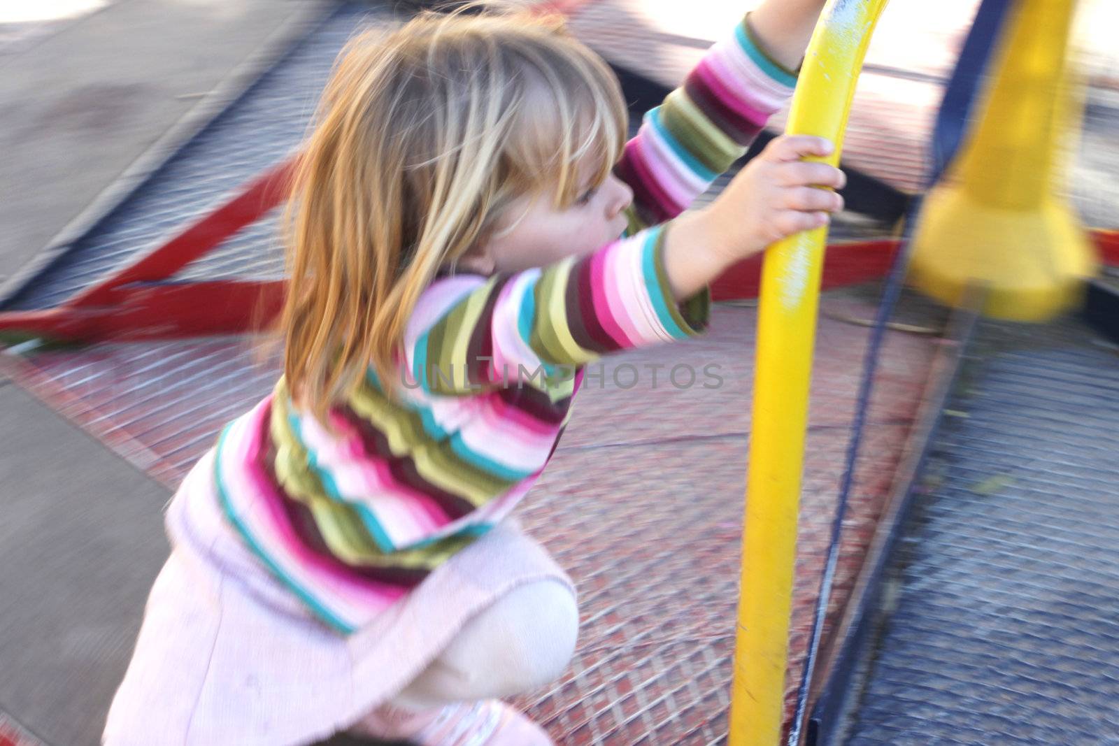 A girl on a merry go round. Motion blur







A girl pushing a merry go round