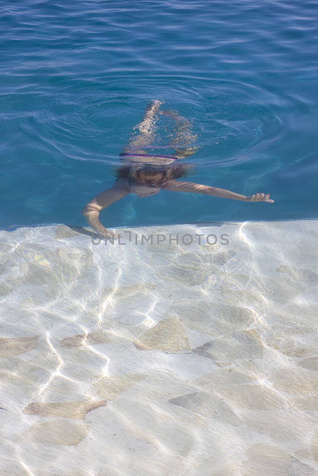 A young girl diving in a clear swimmingpool with copy space