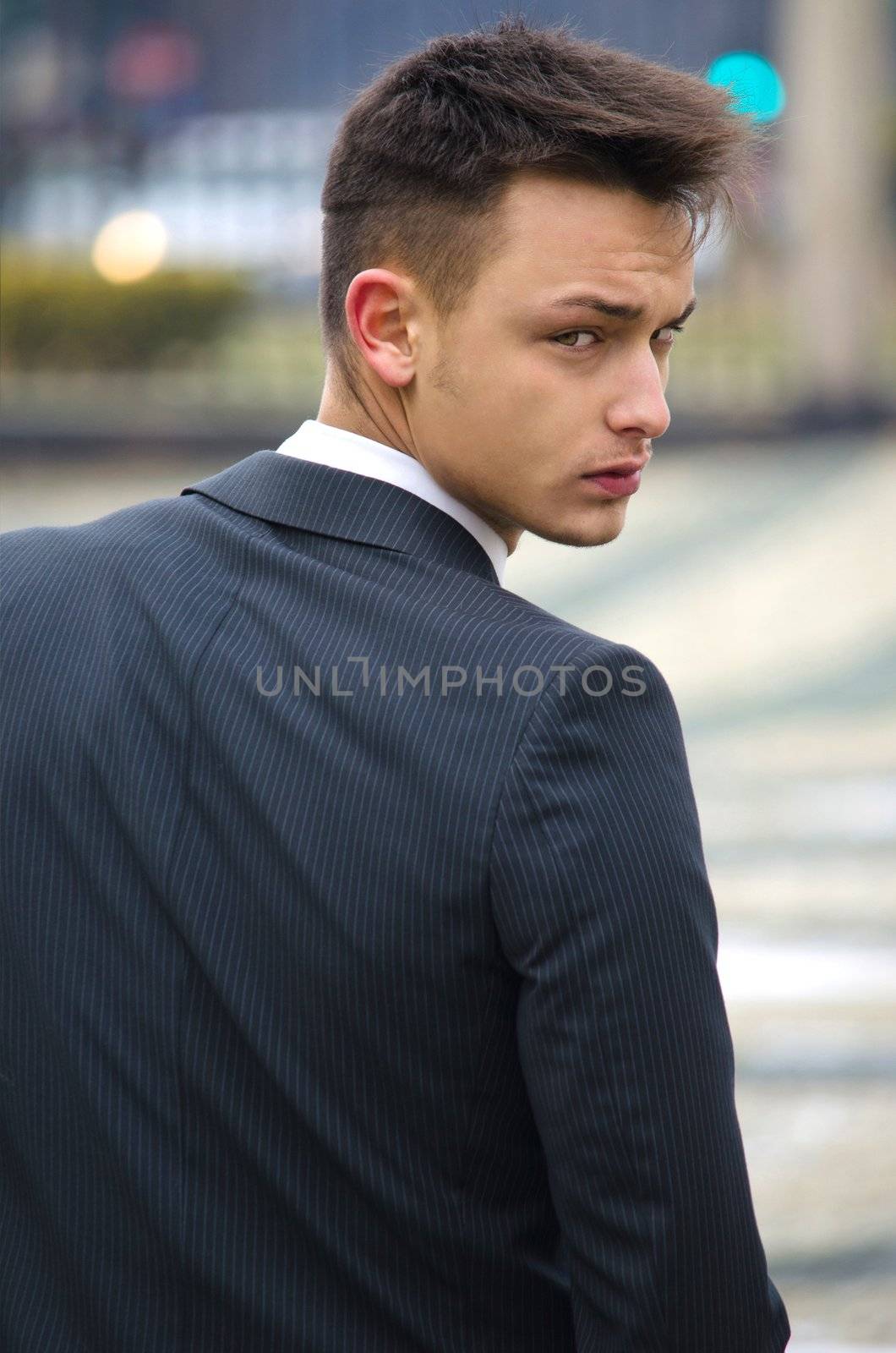 Attractive young man in suit seen from the back looking in camera
