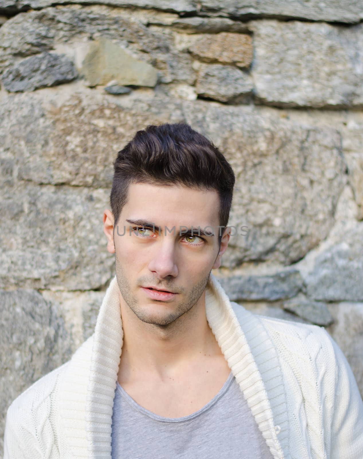 Portrait of attractive young man outdoors against stone wall by artofphoto