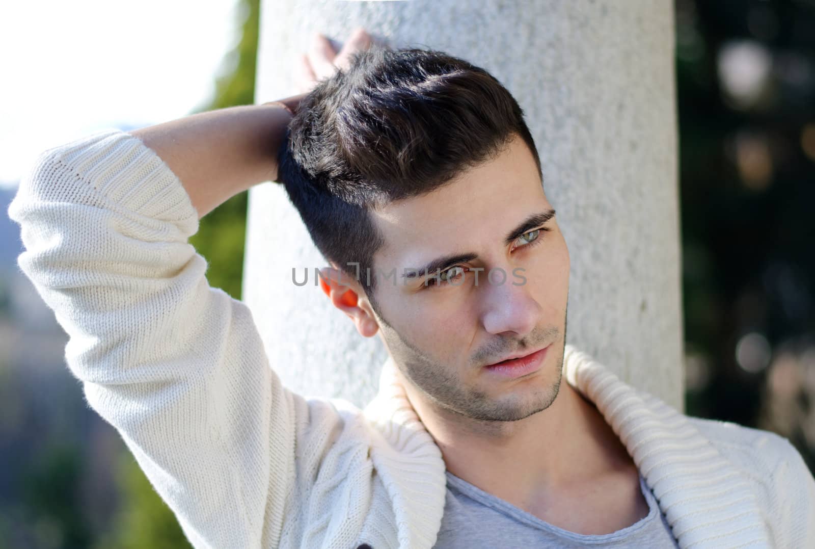 Portrait of attractive young man outdoors against stone pillar