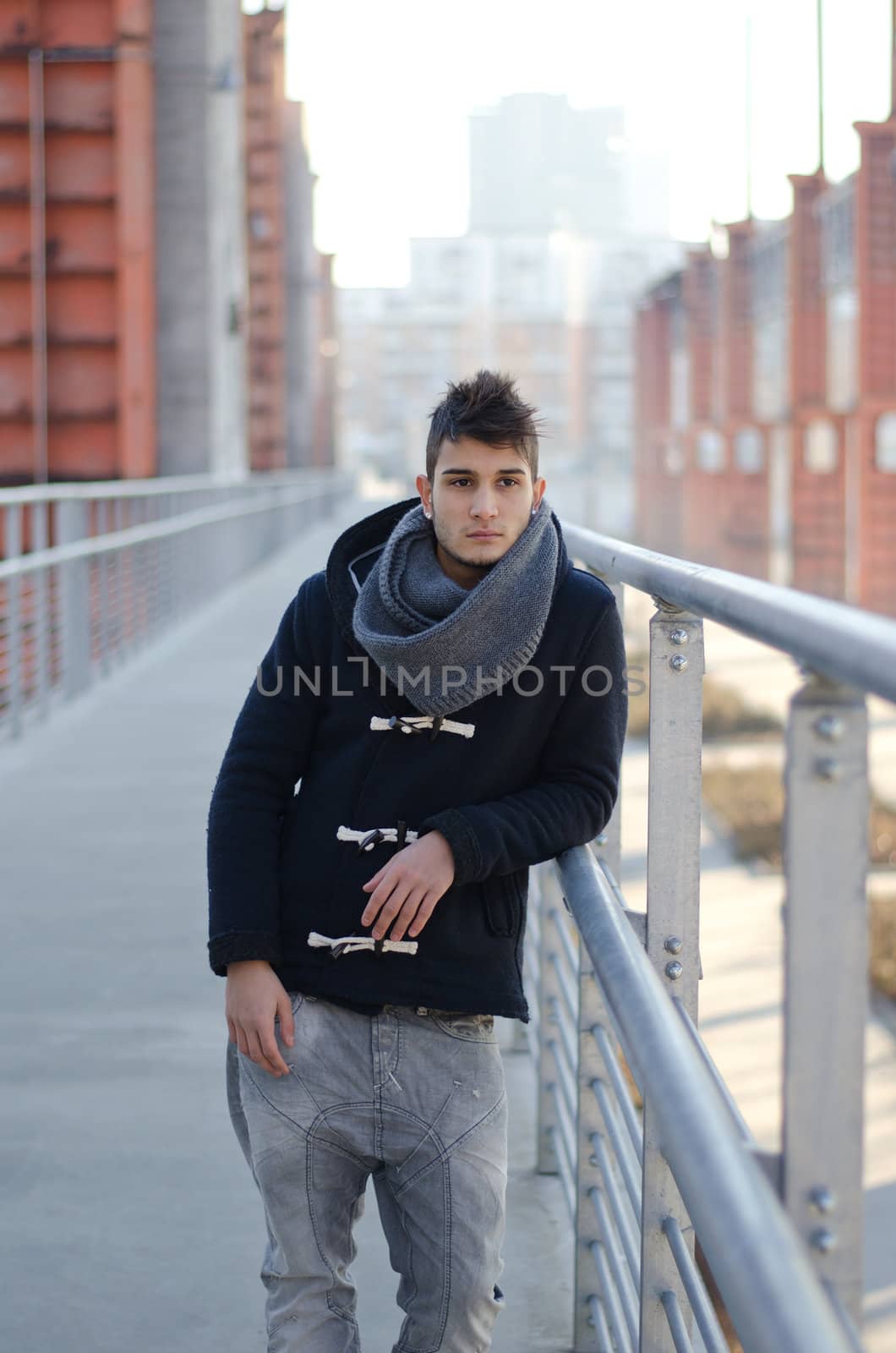 Handsome young man standing in urban or industrial setting, winter clothes