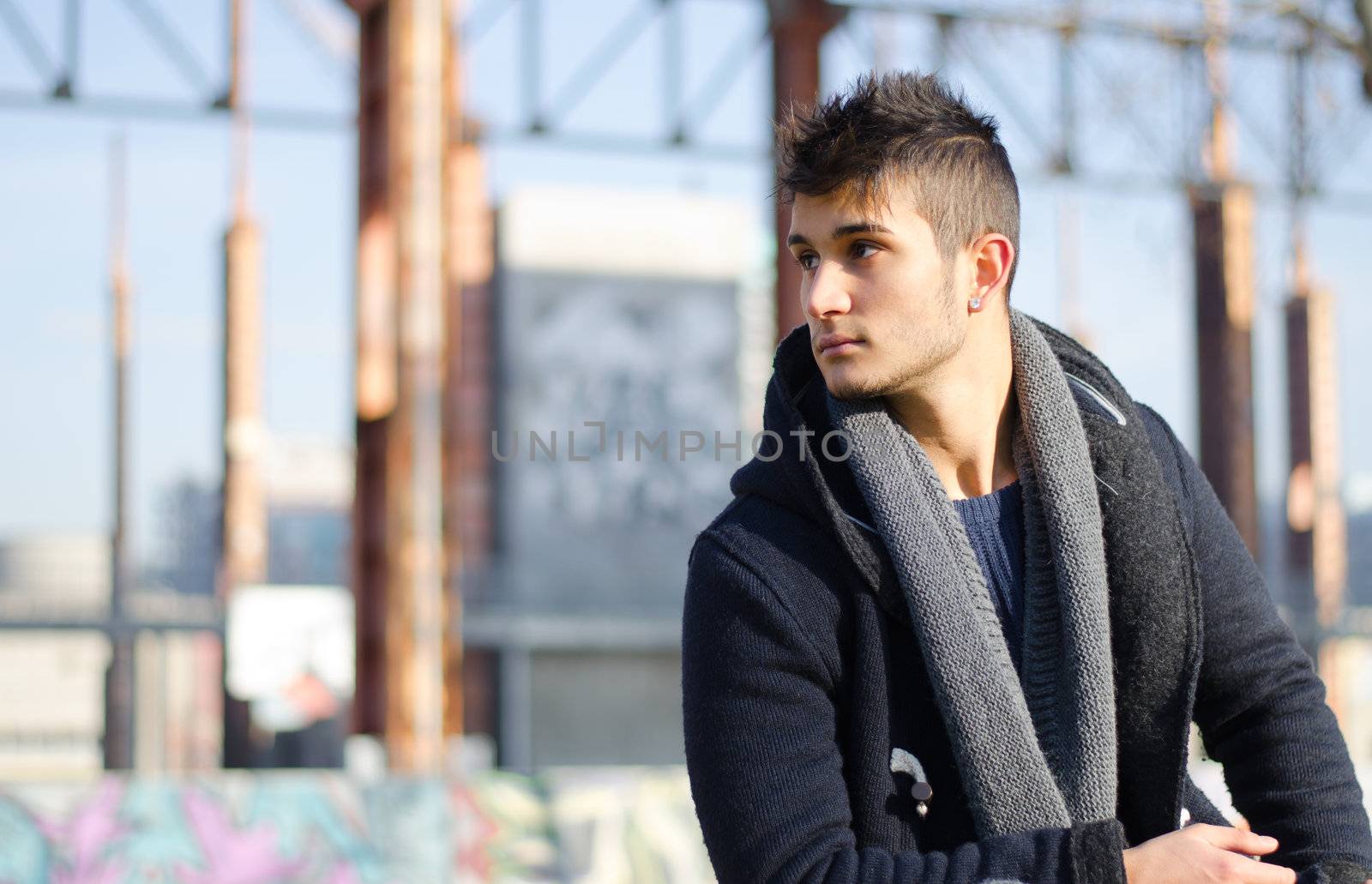 Handsome young man in urban or industrial setting, large copyspace