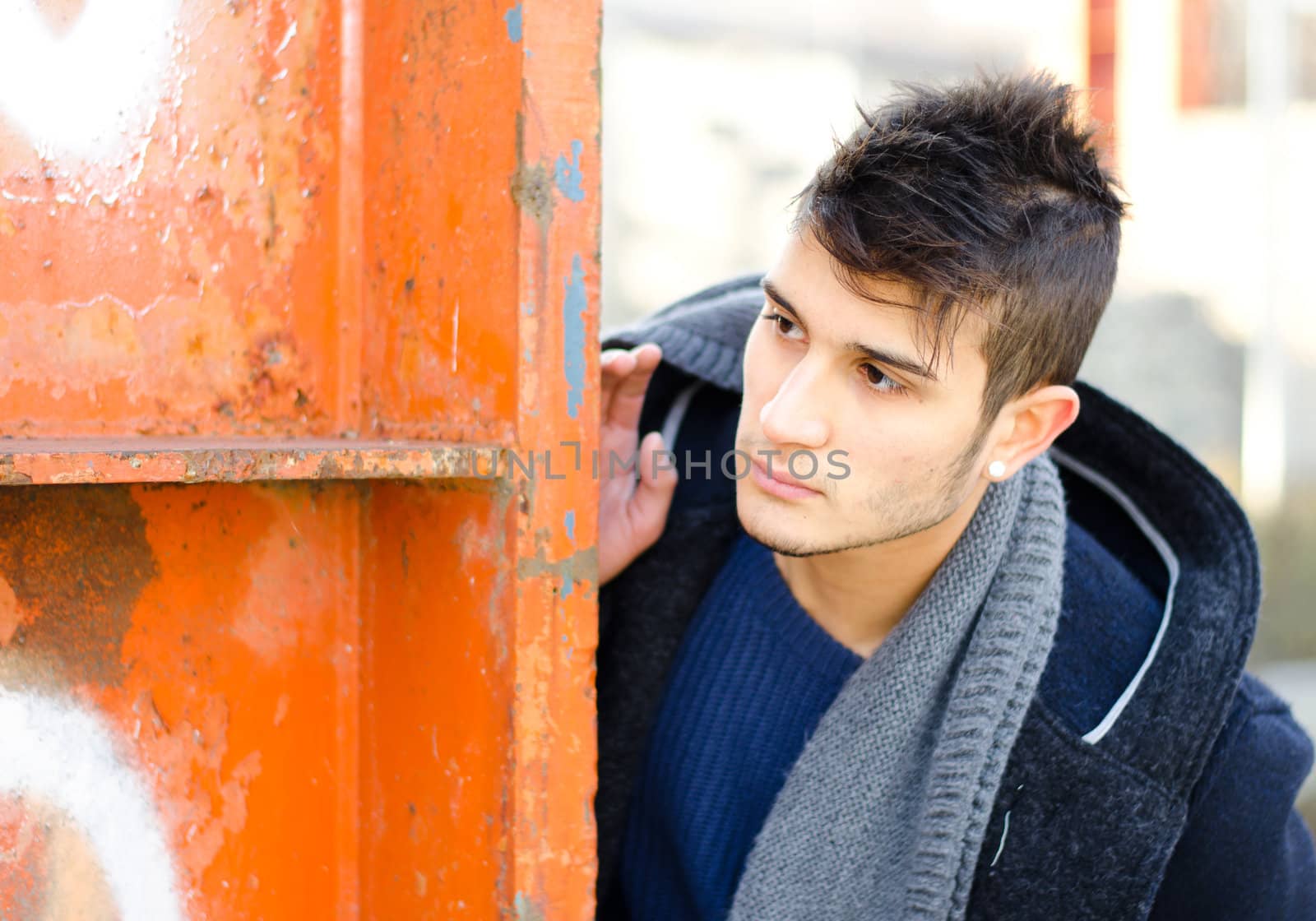 Attractive young man looking beyond orange metal structure