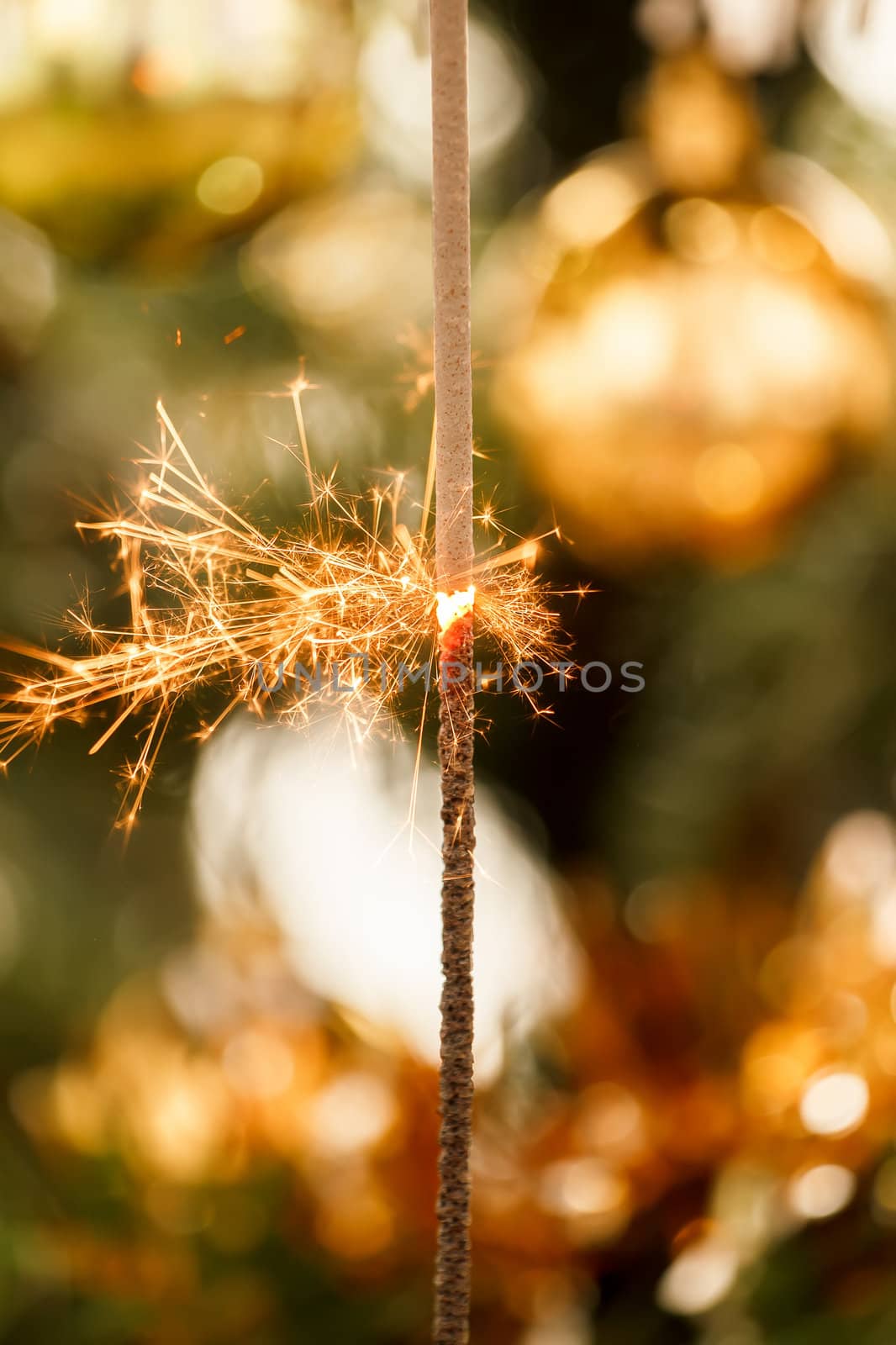 burning sparkler and out of focus christmas tree 
