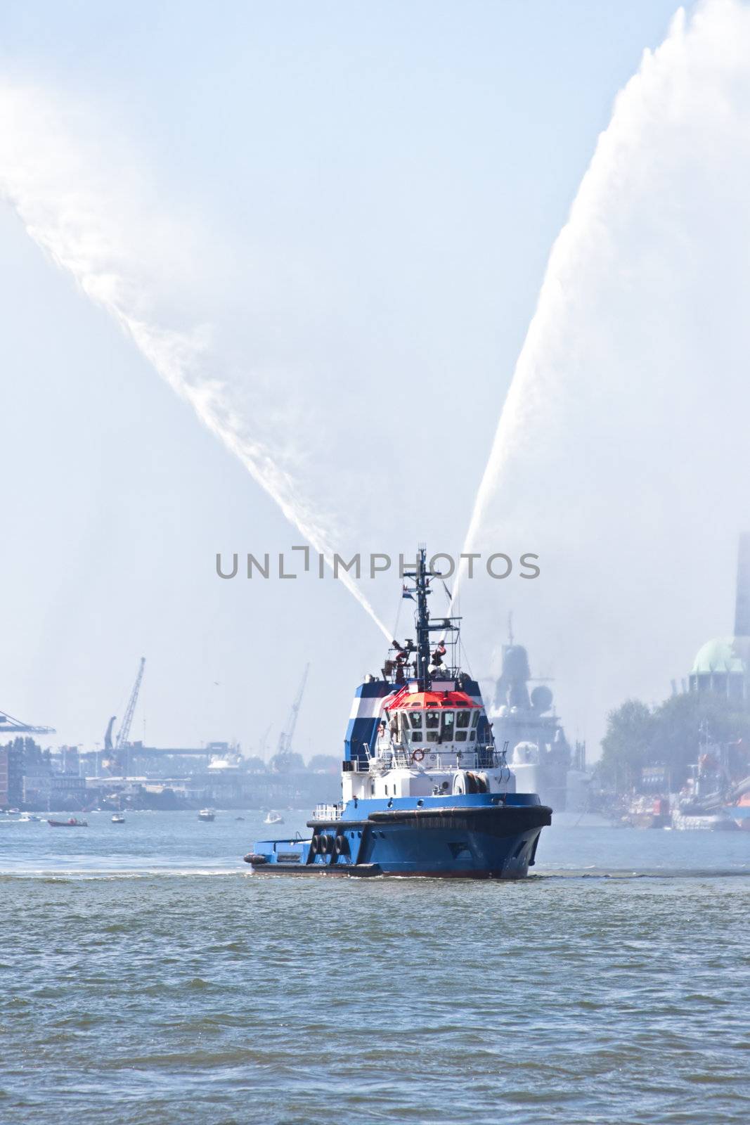 Blue fire boat on  harbor  spraying bright streams of water in d by devy