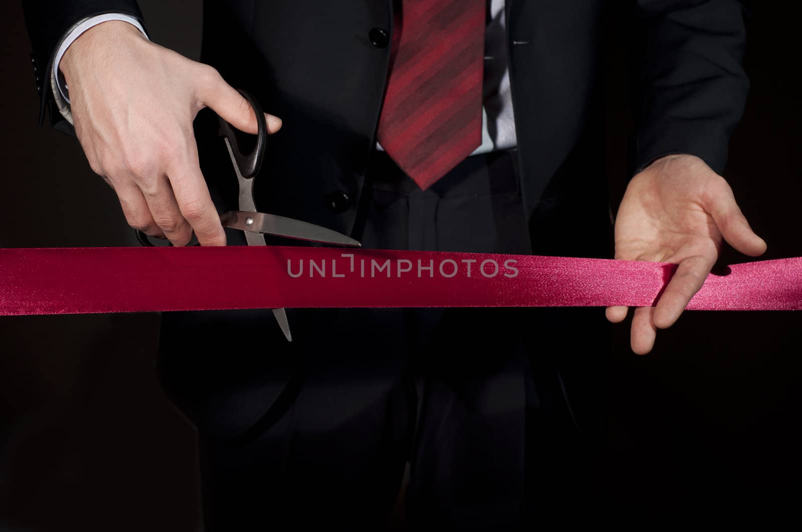 man in a suit, cuts a red tape, opening of event