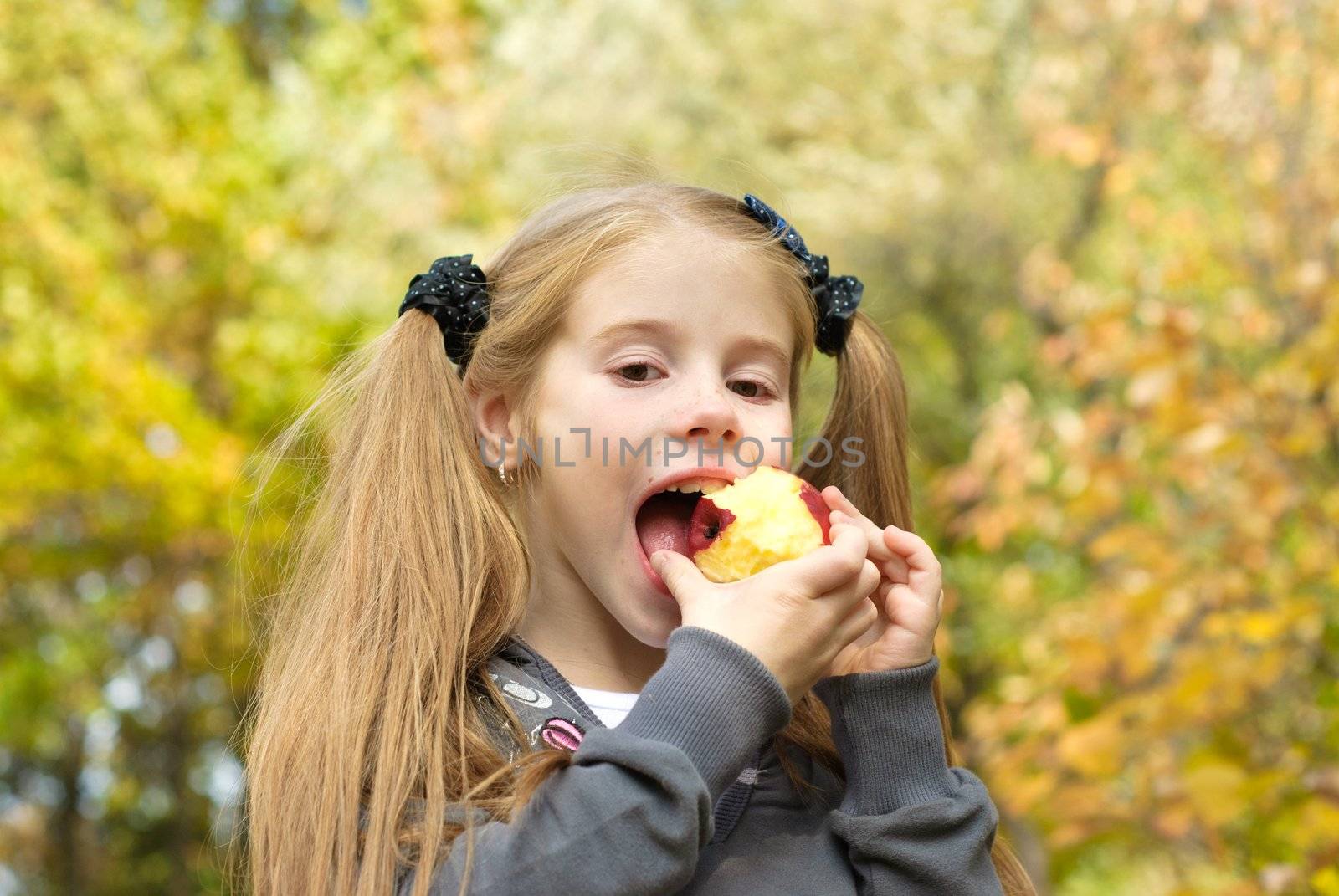 Little girl eating apple outdoors