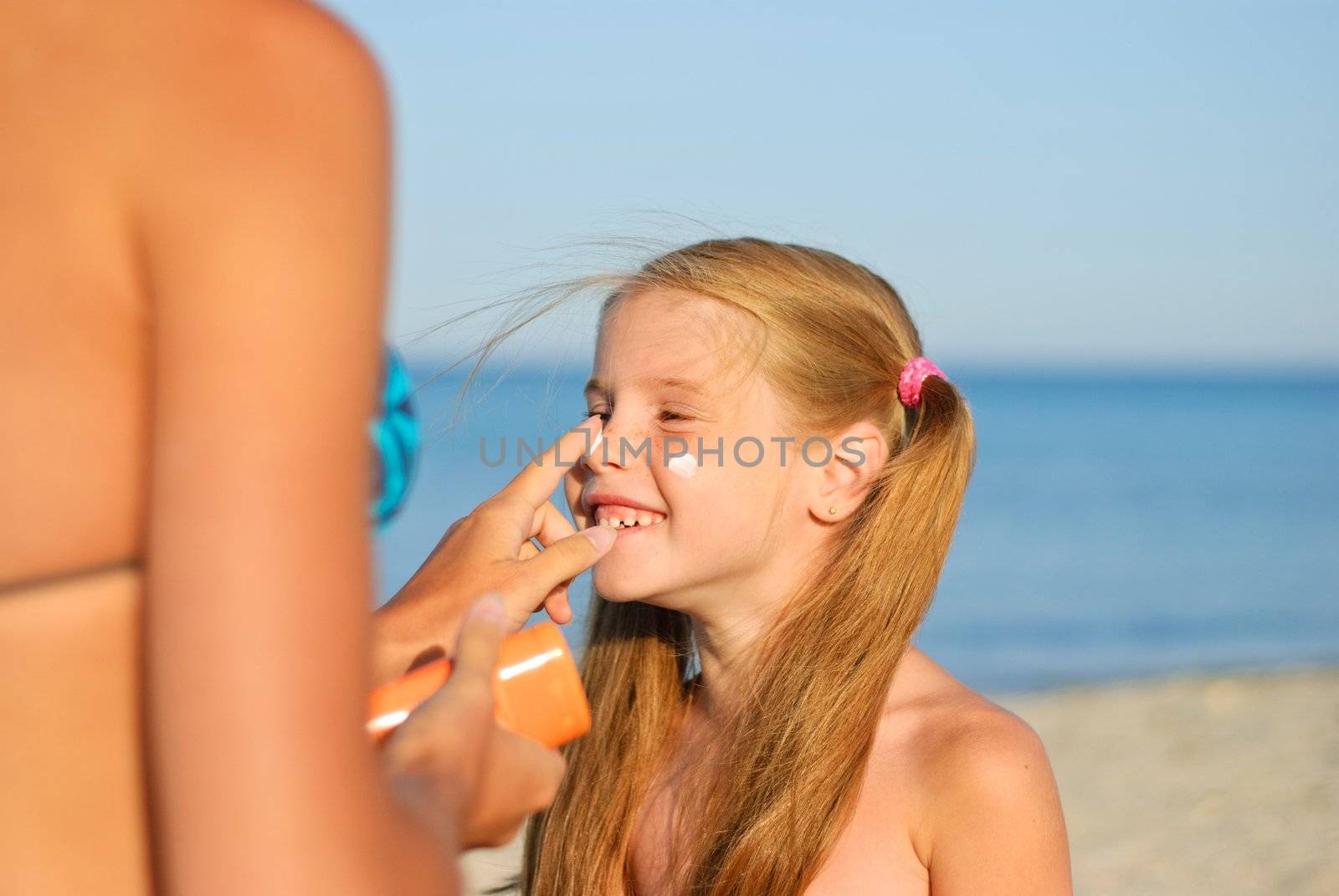 Mother smearing her daughter with sunblock