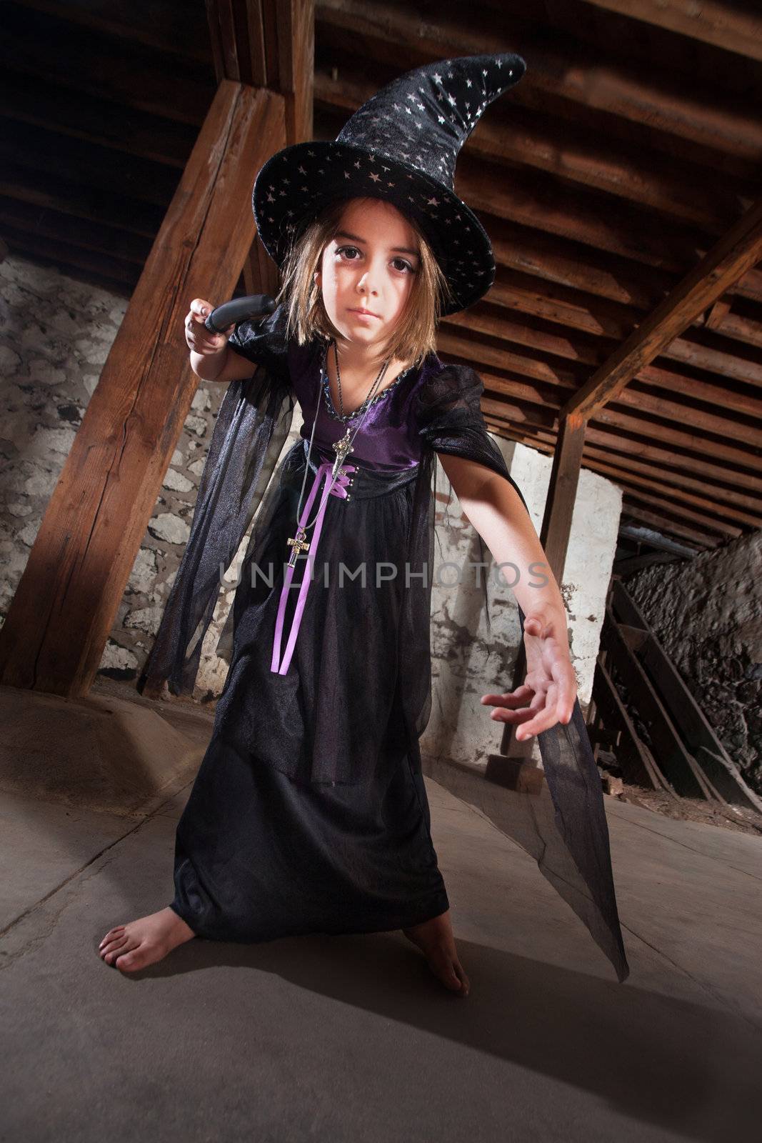 Serious female European child witch pointing her magic staff