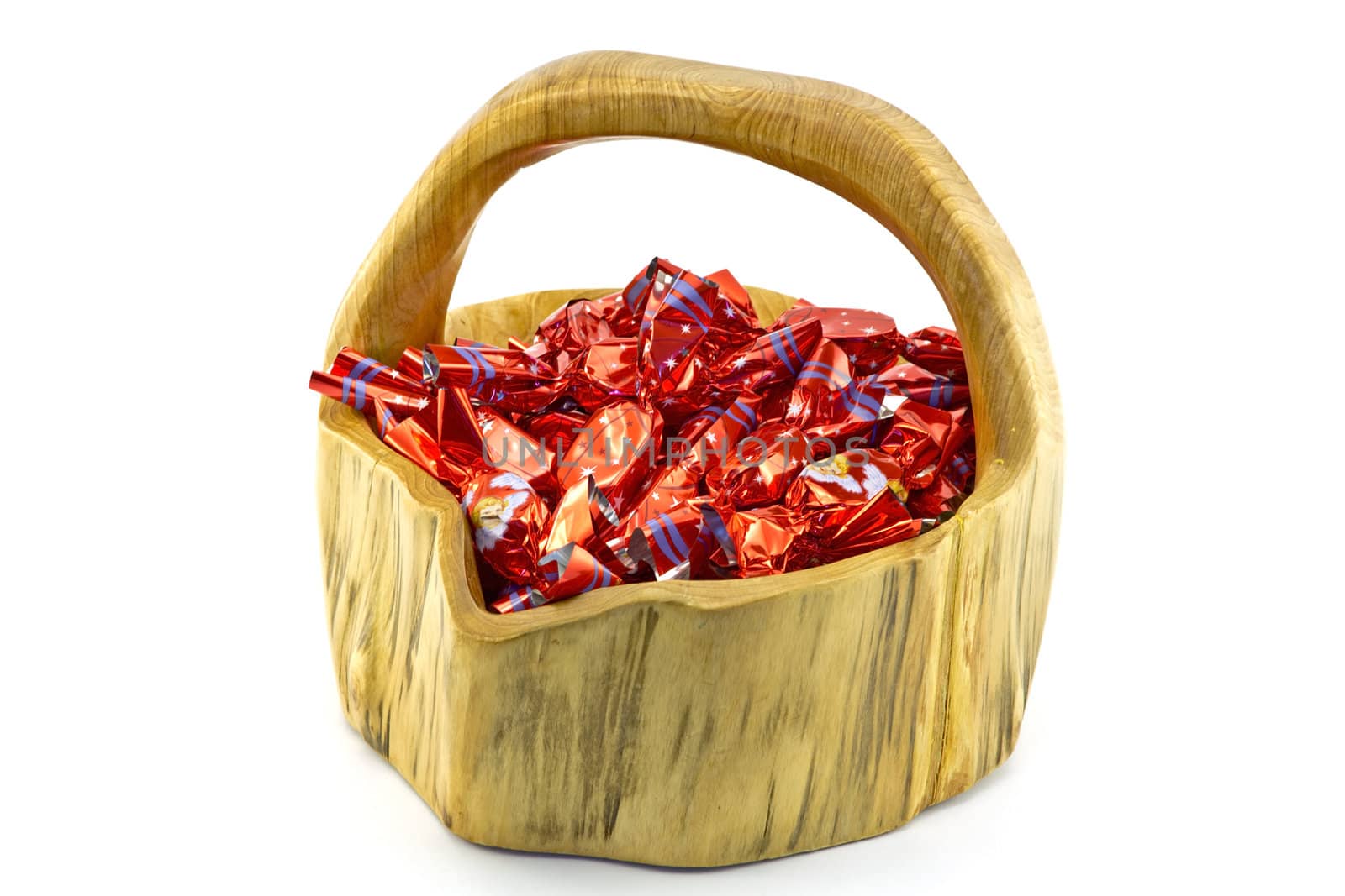 Red christmas pralines in a wooden basket on white background