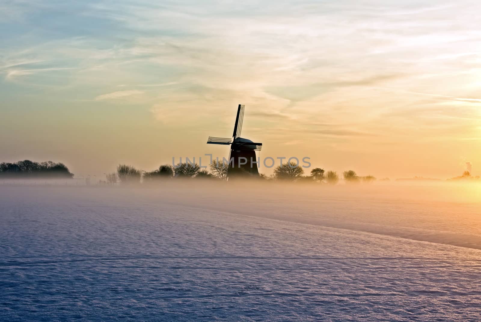 Traditional windmill at twilight with fog and snow in winter in the Netherlands