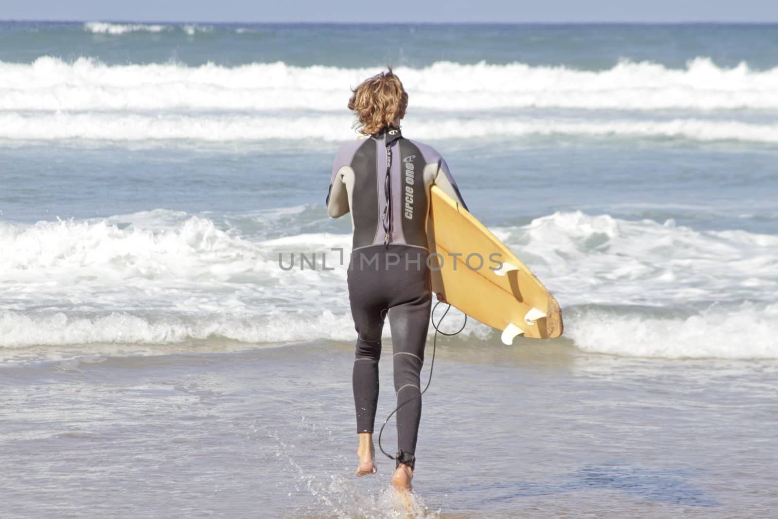 Young surfer is going to surf in the atlantic ocean