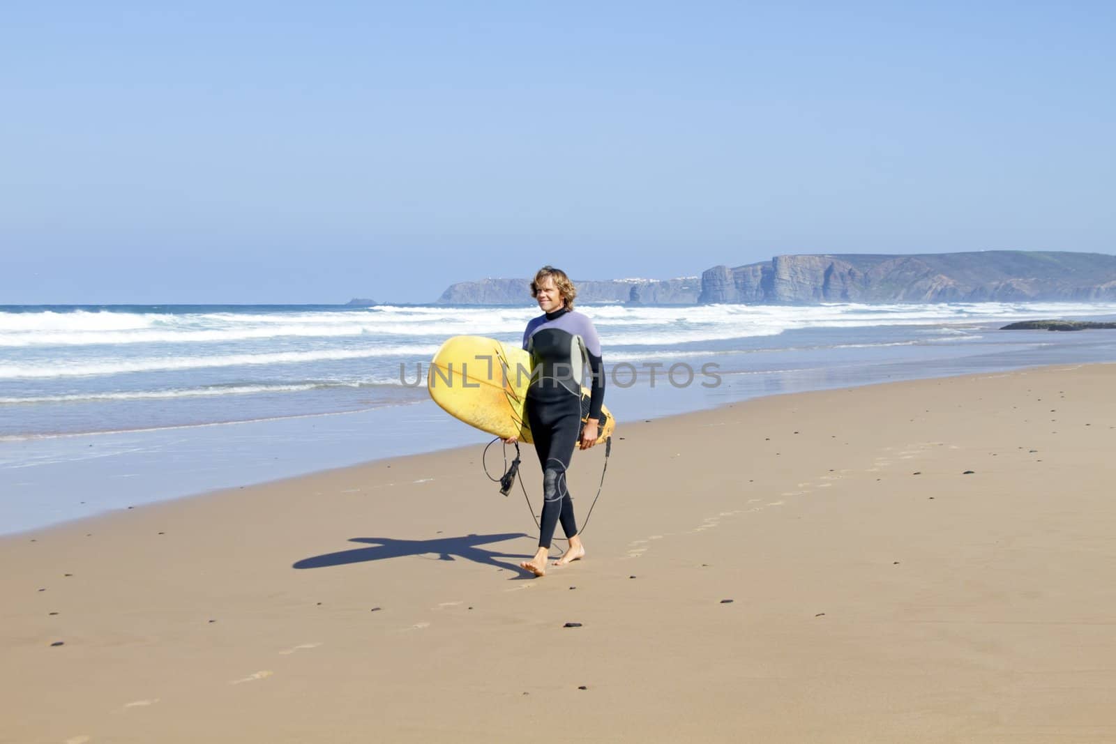 Surfer walking along the beach by devy