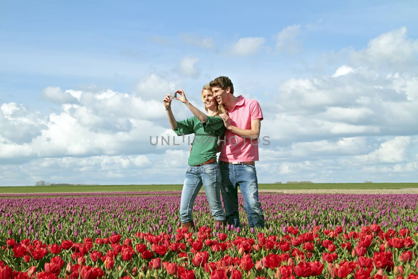 Young happy couple making a picture in the tulip fields  by devy