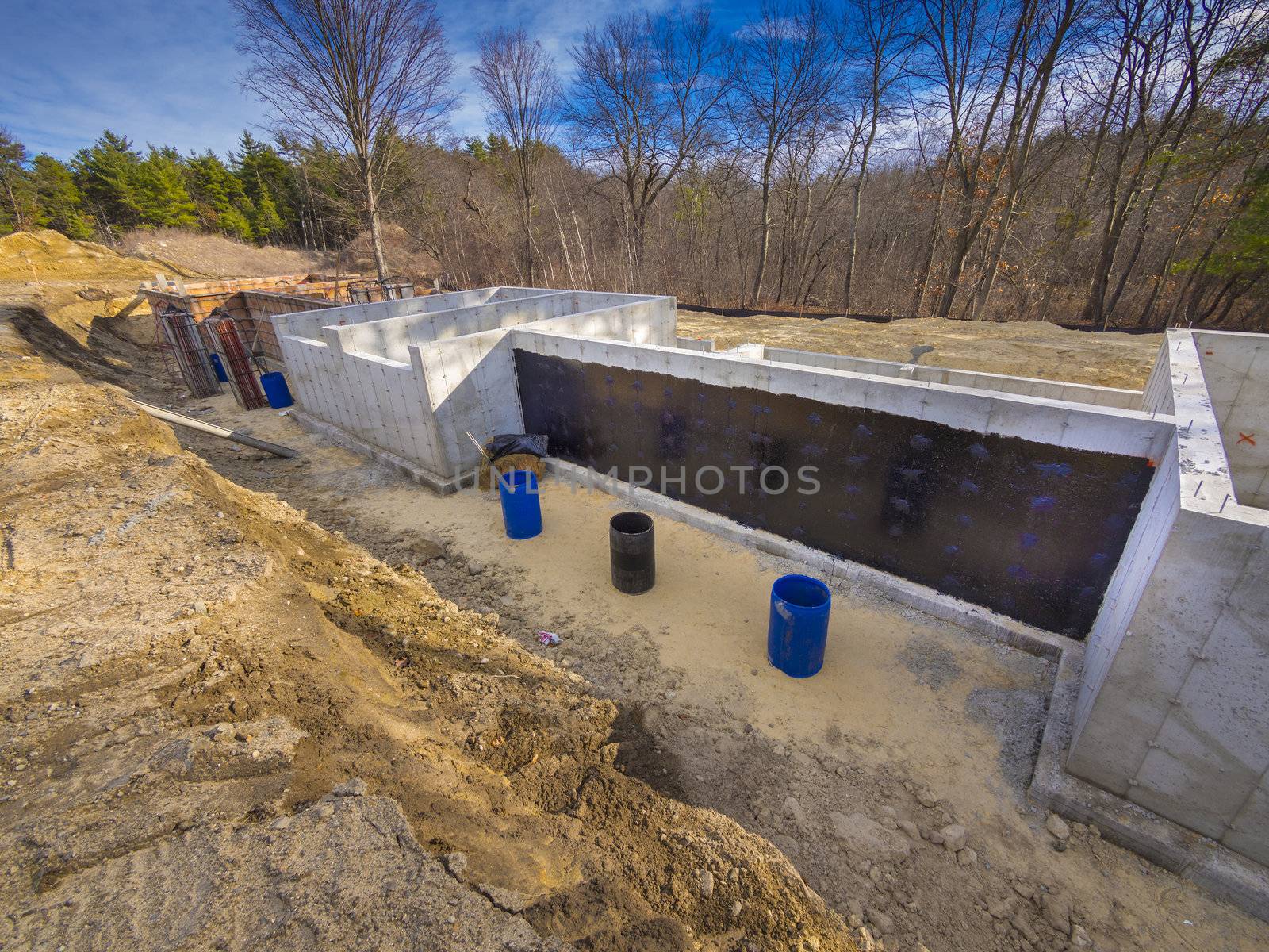 New house foundation freshly poured with waterproofing material applied to wall