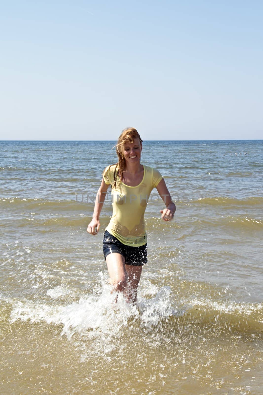 Young woman running out of the water from the north sea in the Netherlands