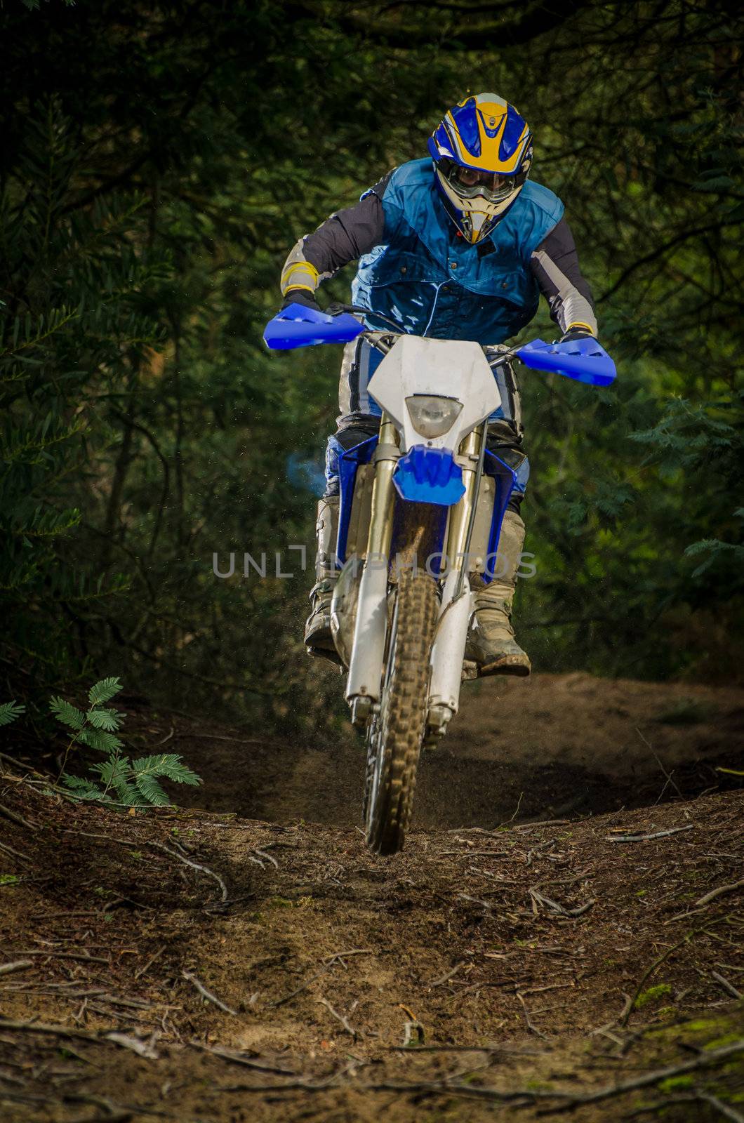 Enduro bike rider on action. Small jamp on muddy terrain.