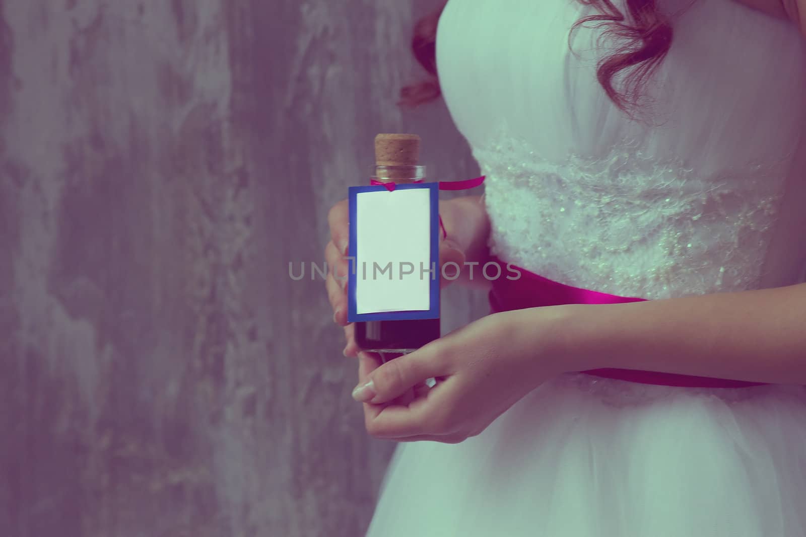 girl in a white dress holding a bottle labeled