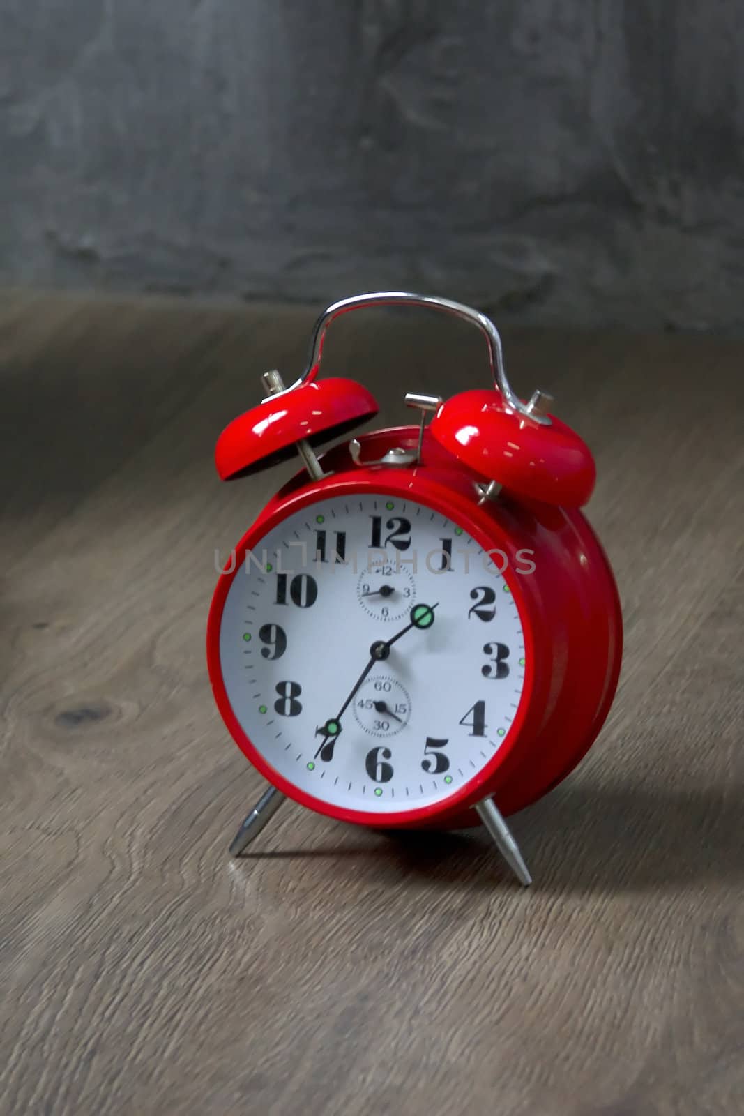 Old red alarm clock on dark floor