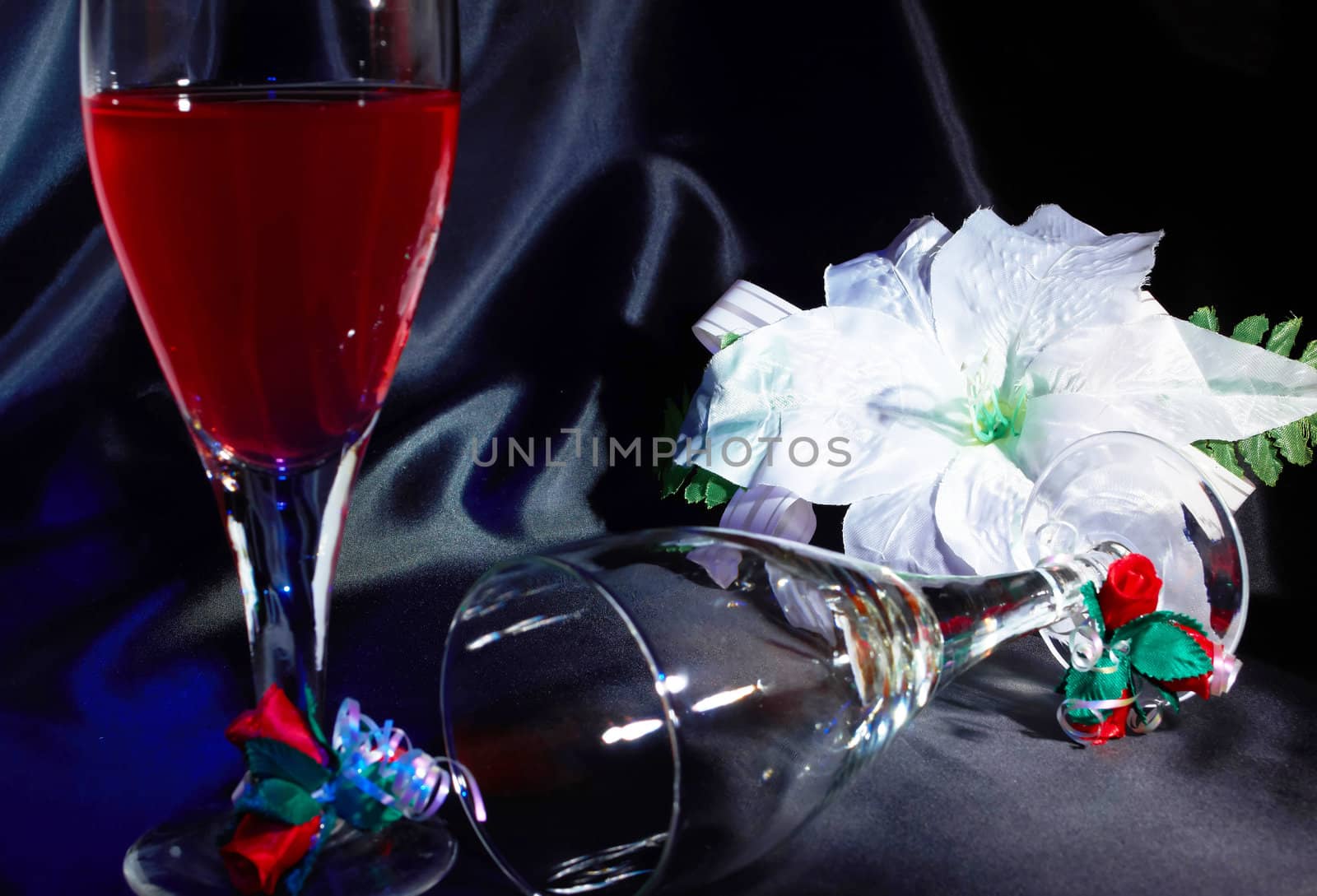 Crystal glass with red wine and white artificial flower