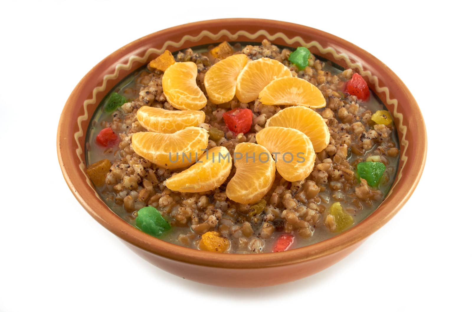 Sweet wheat porridge with dried fruit, lobules tangerine and honey in a clay bowl