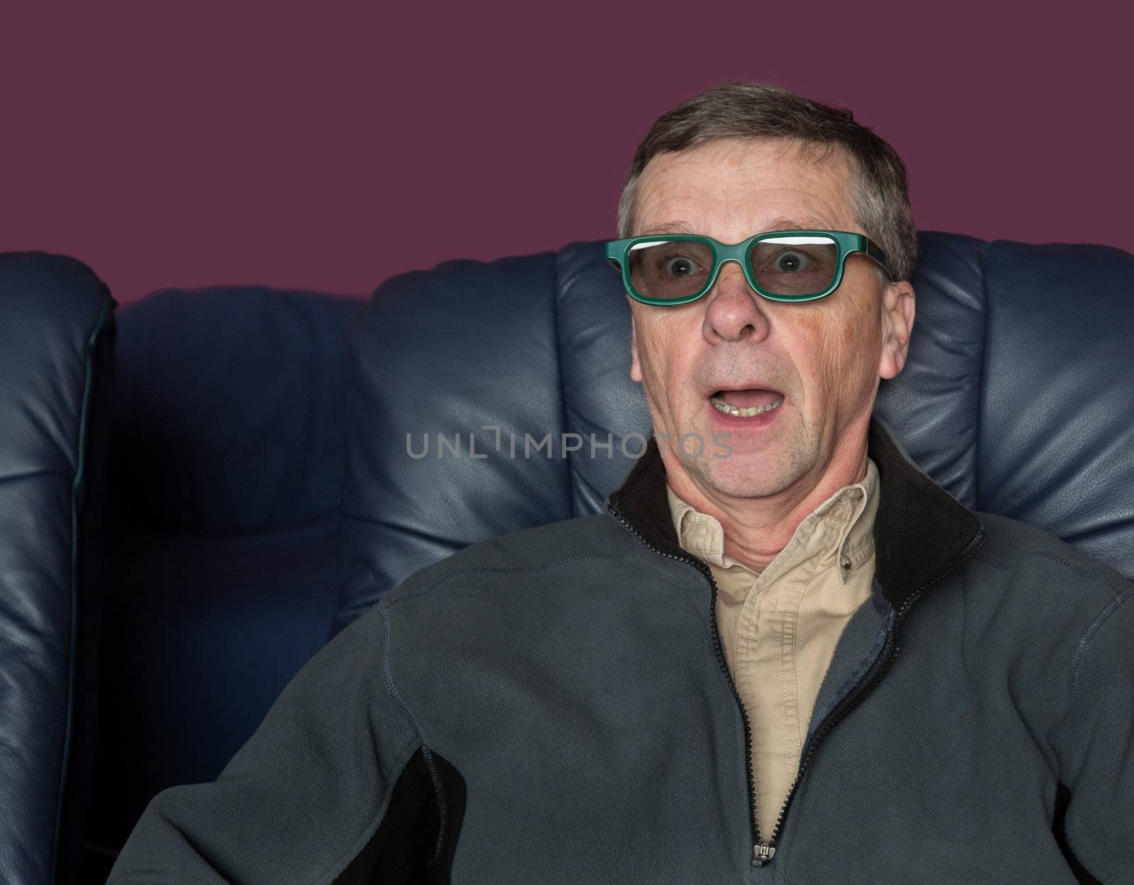 Senior male with shocked expression watching movie in home theater in 3d glasses