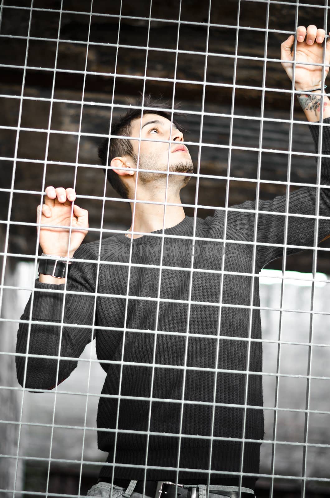 Handsome young man caged behind metal or steel net