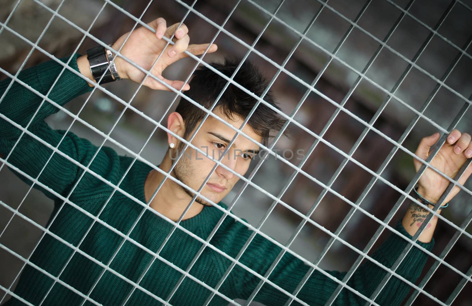 Handsome young man caged behind metal or steel net