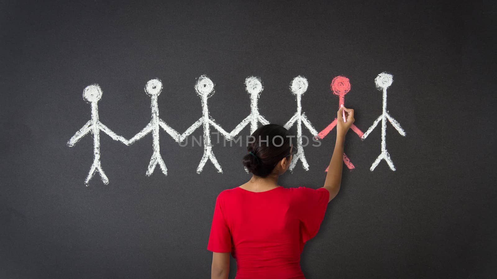 A woman drawing an illustration of stickman with chalk on a blackboard. 