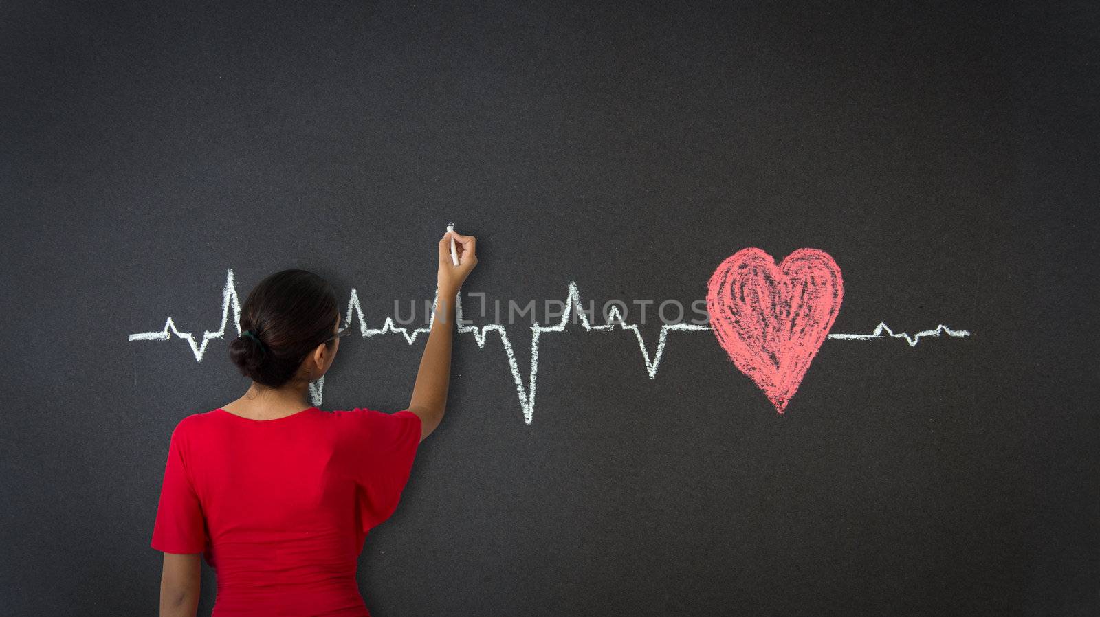 Woman drawing a Heartbeat Diagram with chalk on a blackboard.