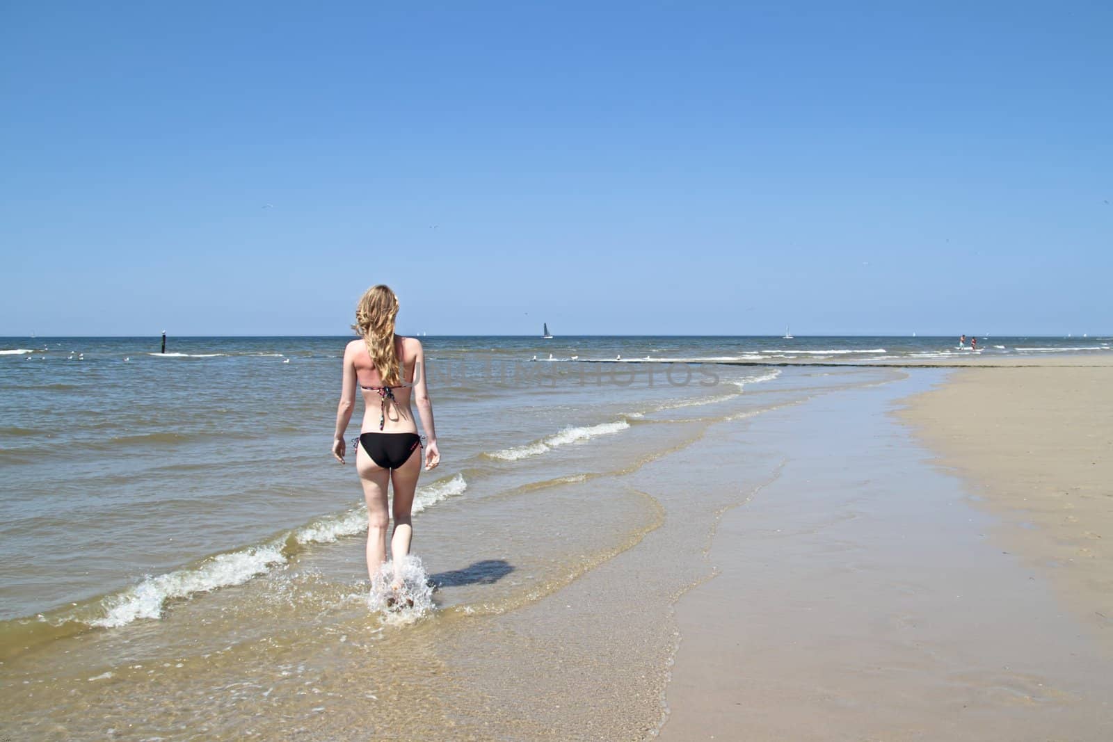 Beautiful young woman walking at the waterfront of the ocean