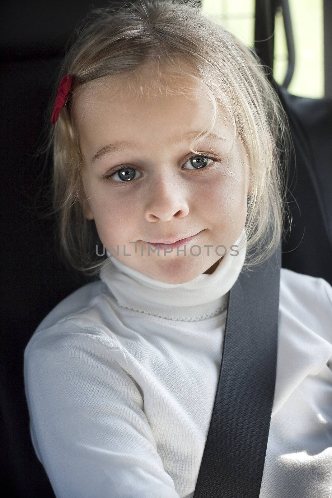 A smiling girl with seat betl in a car