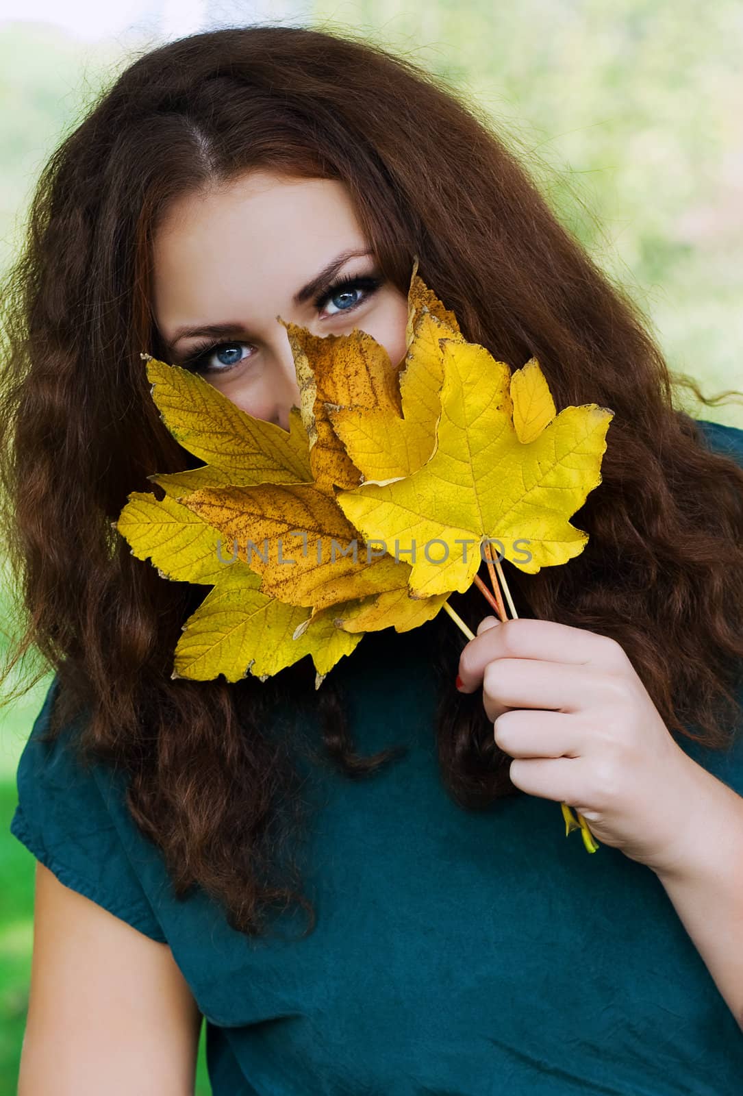 Attractive young woman smiling holding a yellow autumn leaves