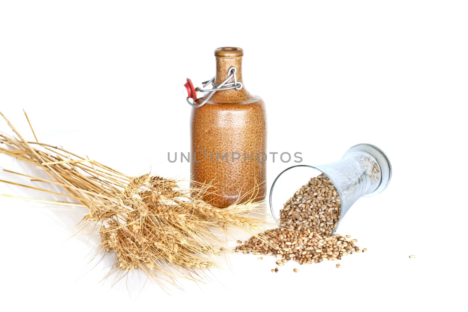 Glass with wheat grains and a jar on a white background