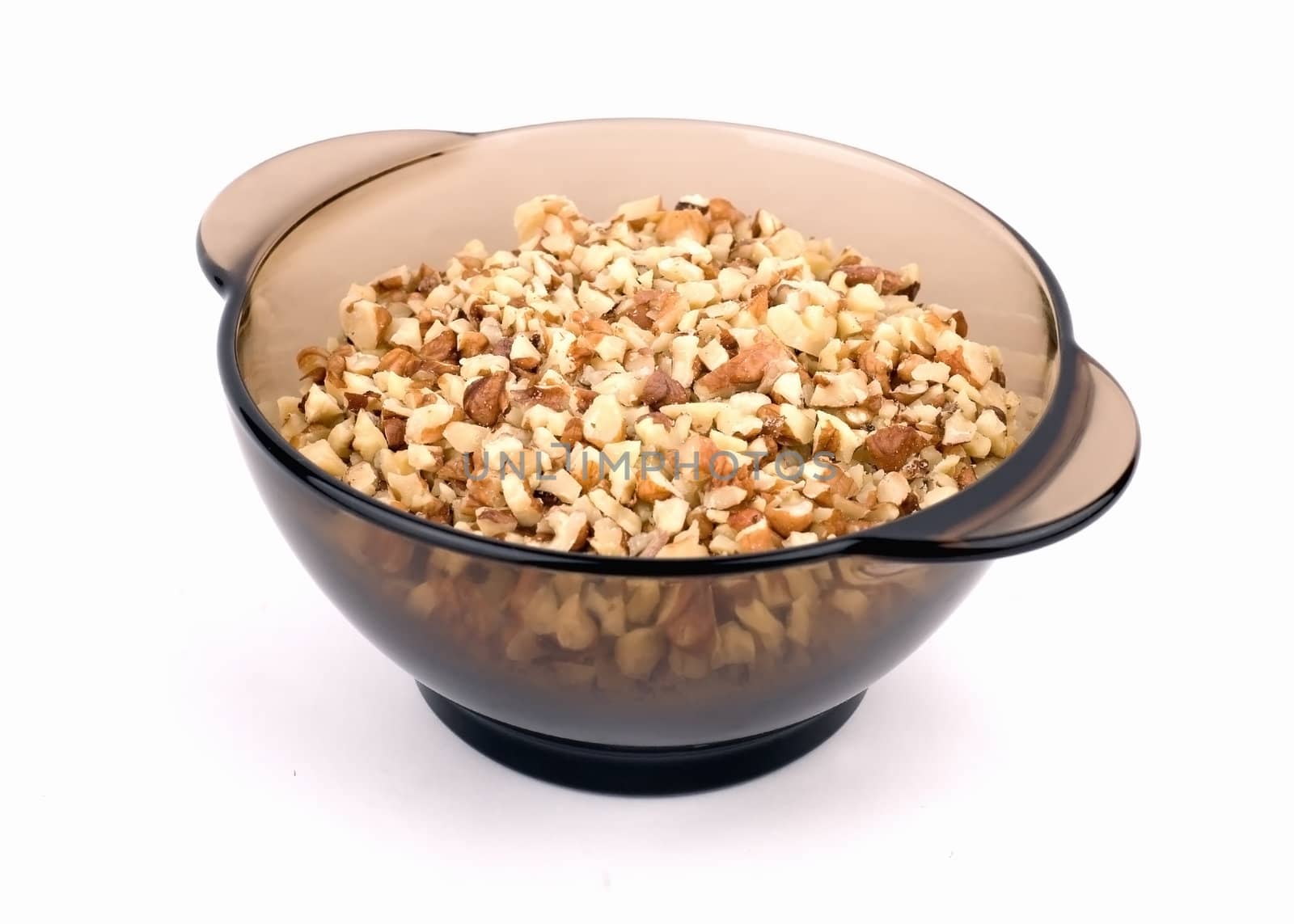 Chopped walnuts in a glass vase brown color on a white background