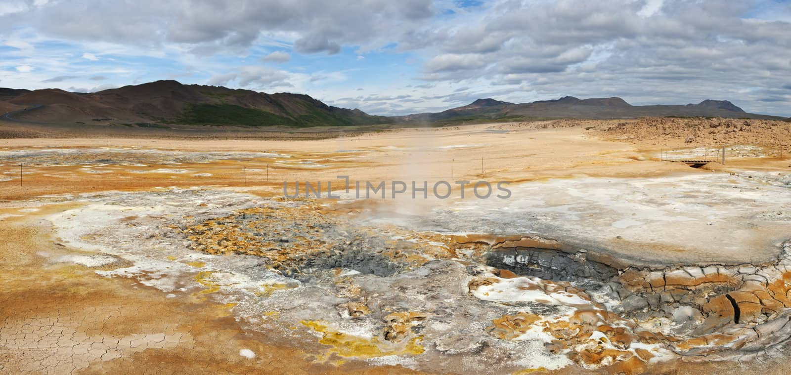Mudpot in the geothermal area Hverir, Iceland. The area around the boiling mud is multicolored and cracked. 