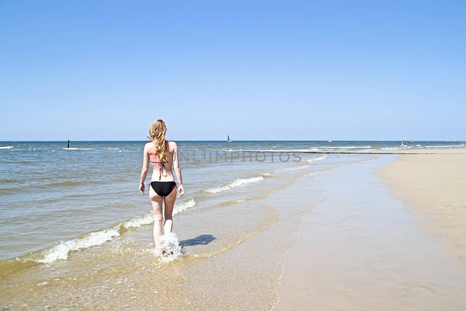 Beautiful young woman walking at the waterfront of the ocean by devy