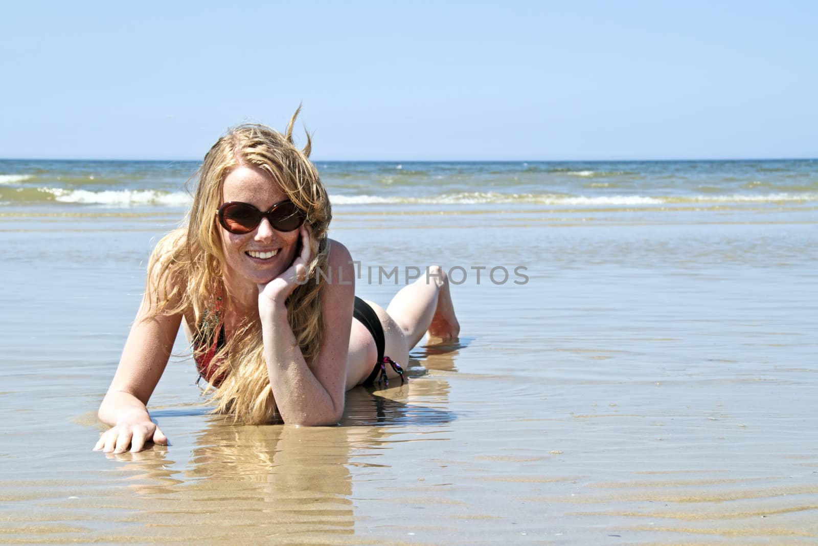 Beautiful blonde woman relaxing at the waterfront of the north sea in the Netherlands