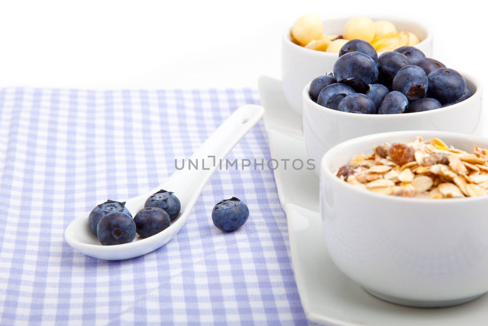 fresh blueberry in white porcelain spoon with bowl of cornflakes, on serviette