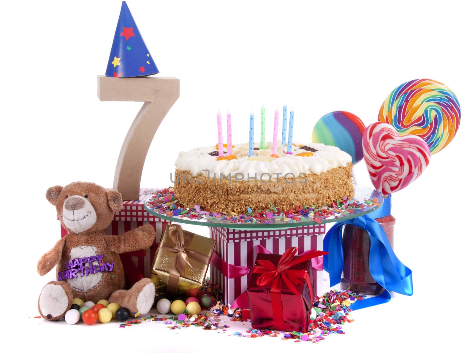 Number of age in a colorful studio setting with paper party hats, a red heart and gifts on a bottom of confetti and sweet cake with candles 