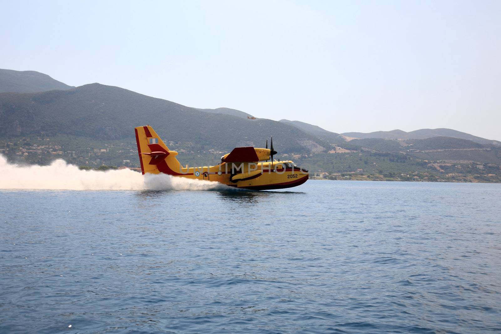 ZAKYNTHOS, GREECE- AUG 1: Canadair CL-415 or Bombardier 415 approaching the sea to take water during big fire at the mountain close to the village Alykes, August 01, 2012 Zakynthos, Greece