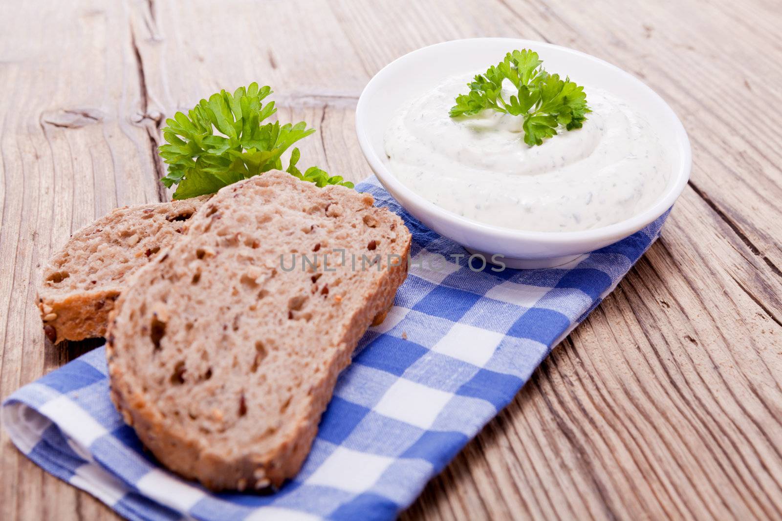 fresh tasty herbal creme cheese and bread on wooden table