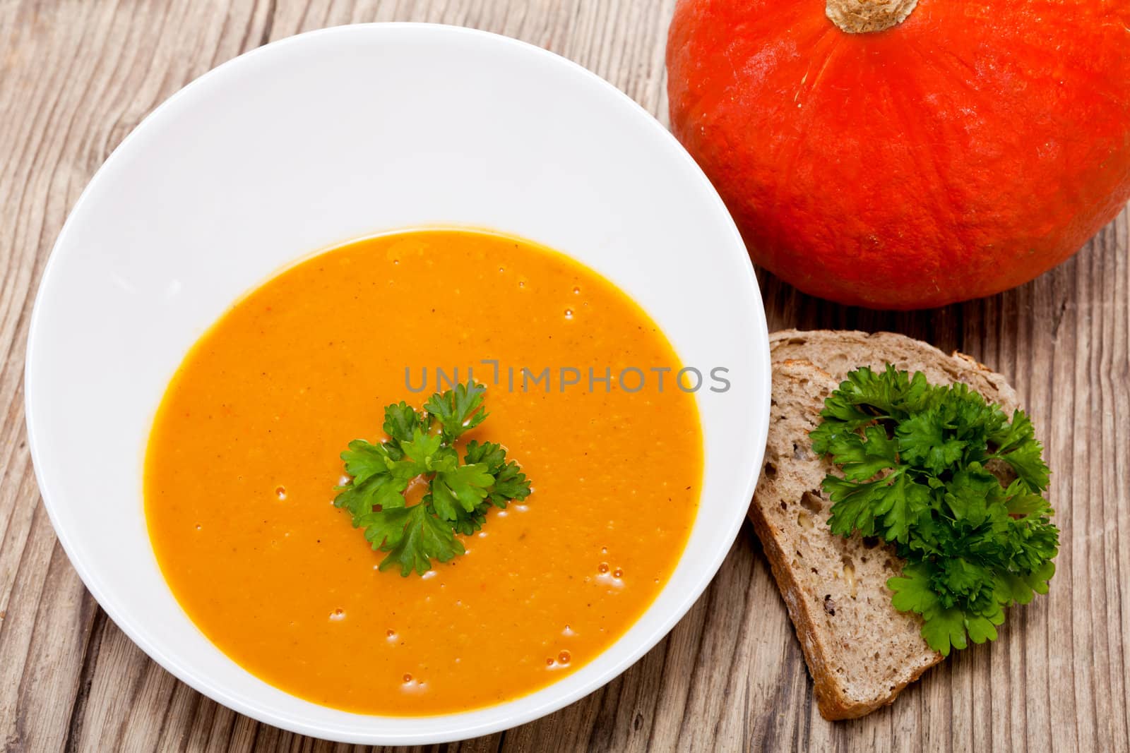 fresh tasty homemade pumpkin soup on wooden table with parsley and bread