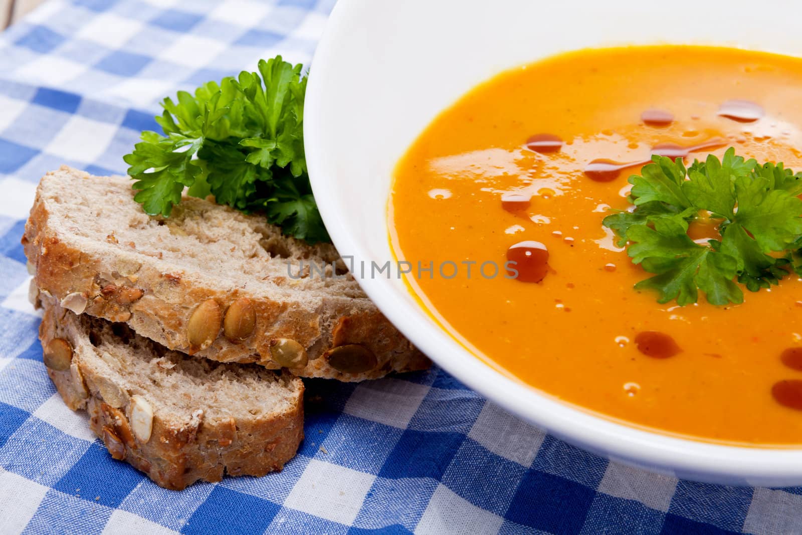 fresh tasty homemade pumpkin soup on wooden table with parsley and bread
