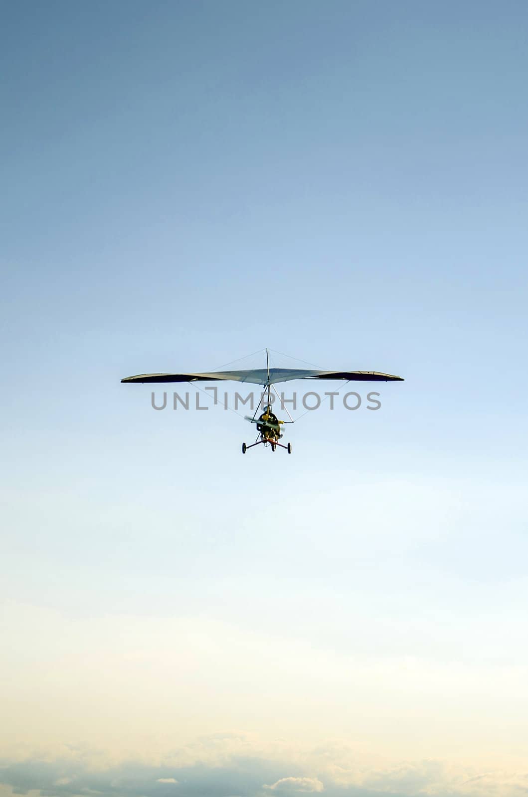 Aerial photo of motorized hang glider flying over clouds.